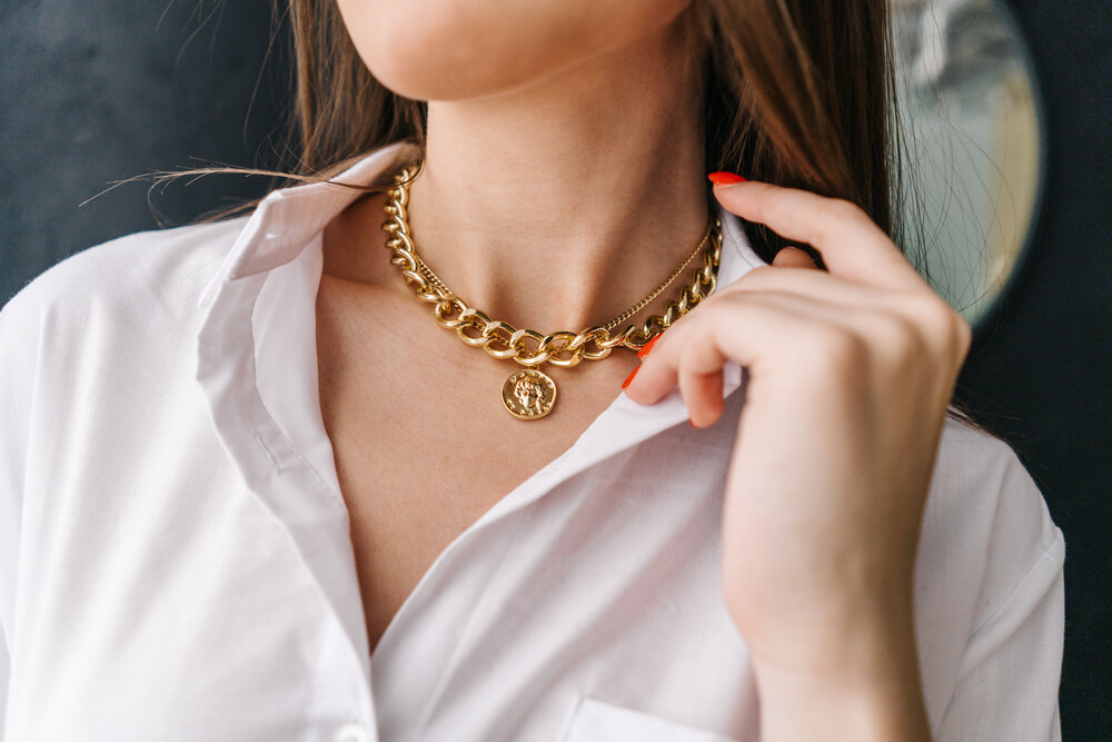 A woman in a white button up shirt wearing a yellow gold chunky chain necklace