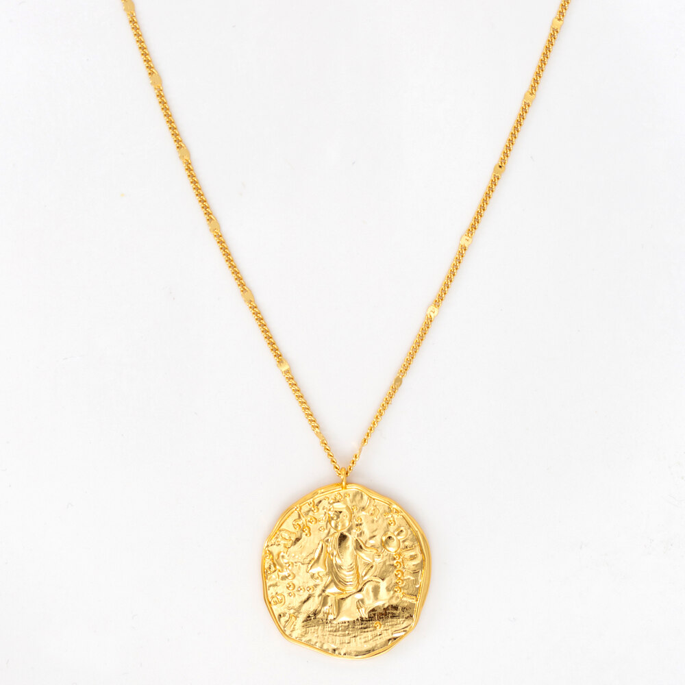 A yellow gold rustic medallion necklace against a white background
