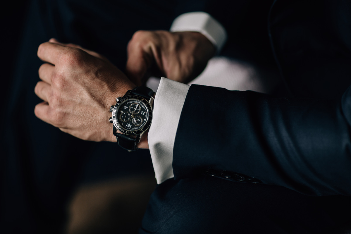 A man in a dark suit wearing a black watch
